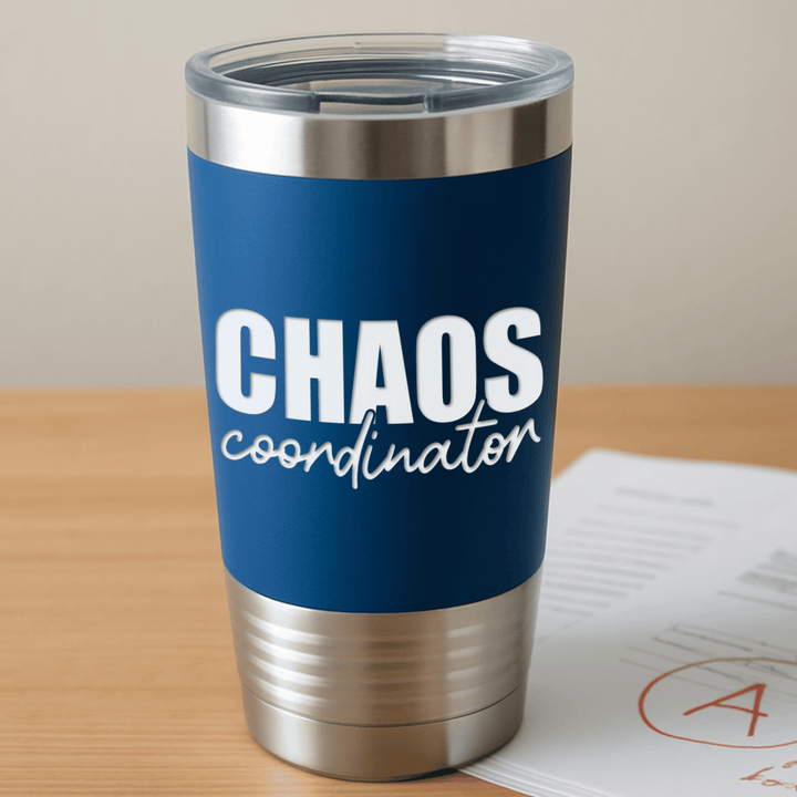royal blue tumbler with 'chaos coordinator' engraved in white sitting on a teacher's desk with a graded paper with an A grade circled on it