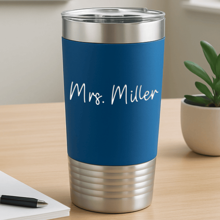 royal blue tumbler with 'Mrs. Miller' engraved in a white modern script sitting on a modern teacher desk