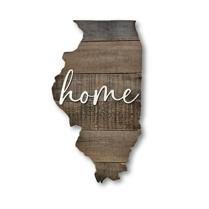 Wooden cutout of the state shape of Illinois with 'home' written on it in 3D white script, on a white background