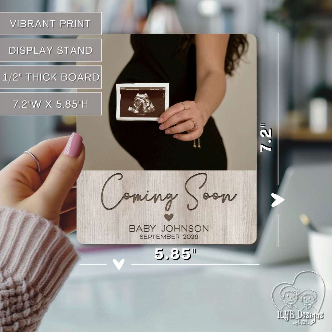 coming soon baby name announcement photo keepsake gift being held in hand to show size of 5.85 inches by 7.2 inches. Text describes photo board as having vibrant print, display stand, 1/2 inch thick board.