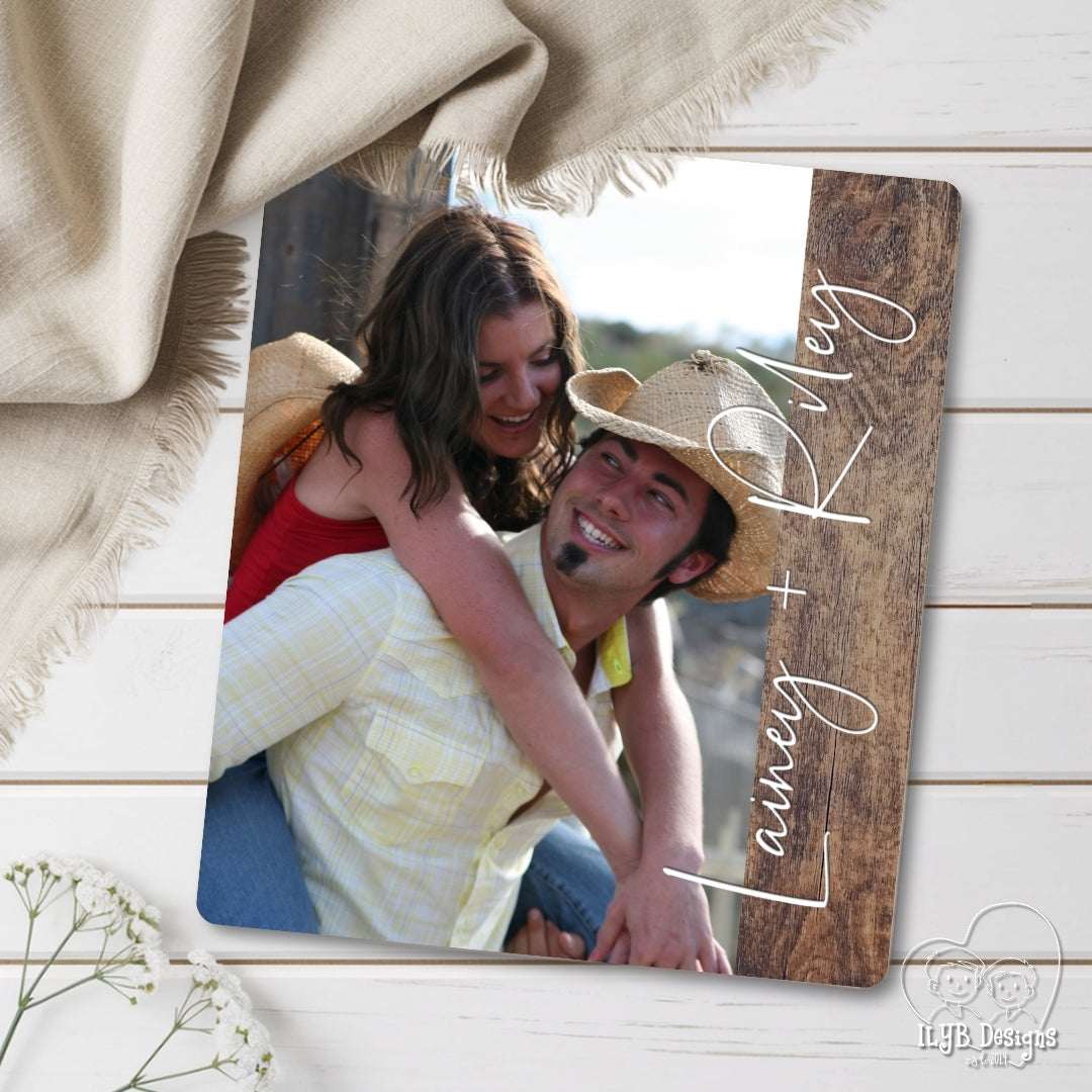 Wooden photo frame with a couple's photo and 'Lainey + Riley' text, placed on a wooden surface.