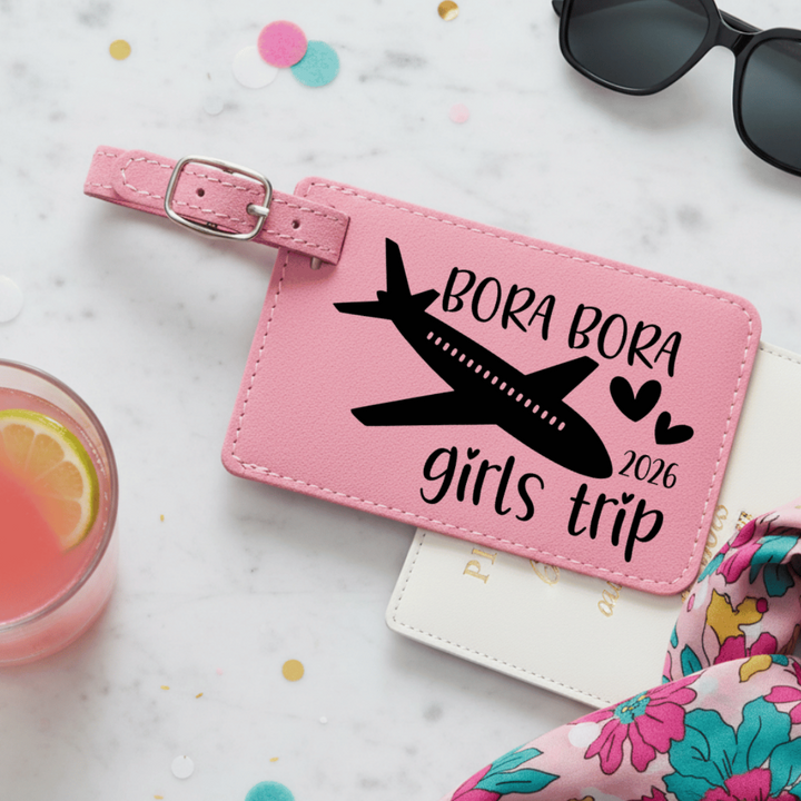 Pink 'Bora Bora girls trip' luggage tag with sunglasses, drink, and scarf on a light background