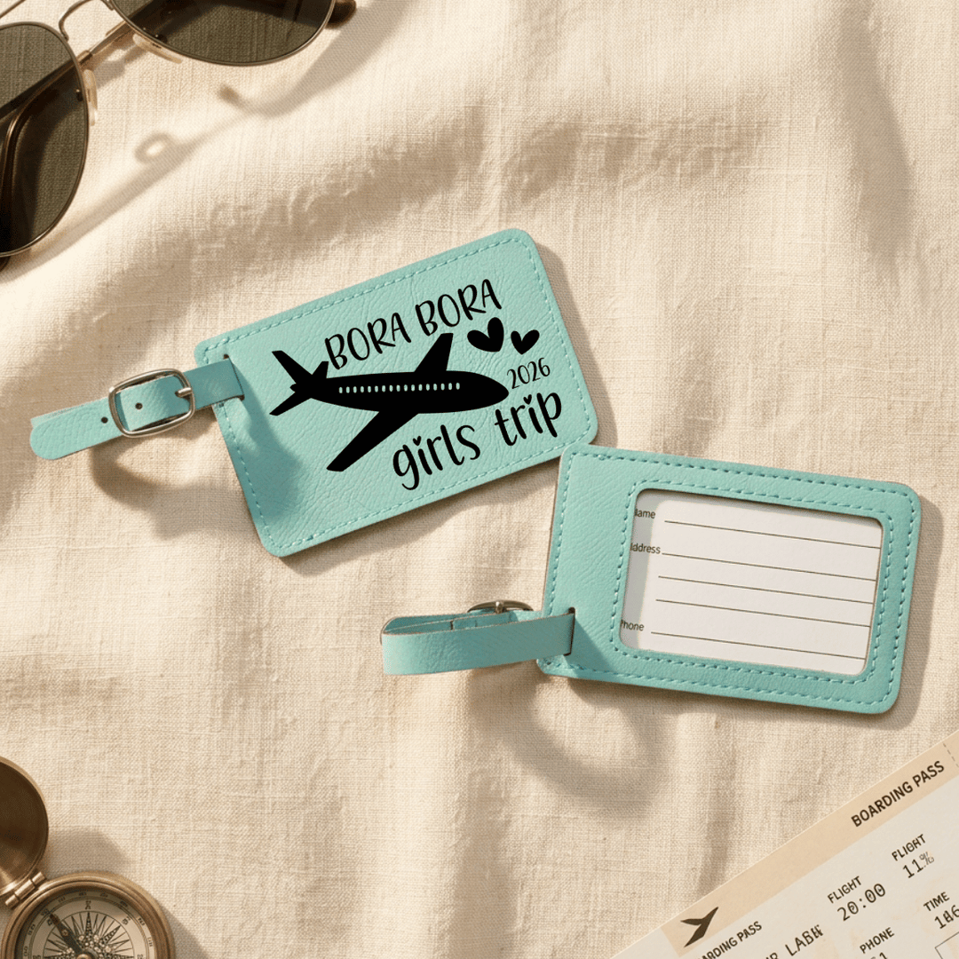 Two turquoise luggage tags with airplane design and text on a beige fabric background.