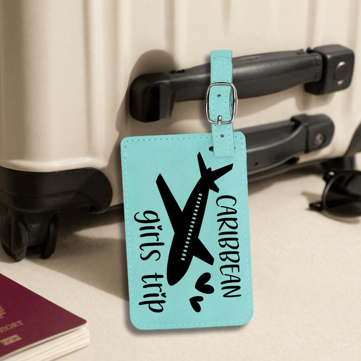 Luggage tag with airplane and text 'girls trip Caribbean' on a suitcase.