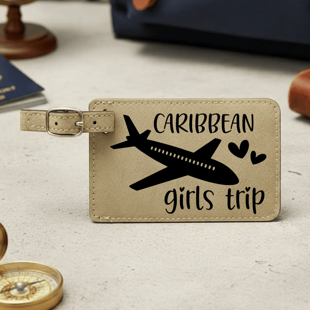 Beige luggage tag with airplane and 'Caribbean girls trip' text on a light surface.