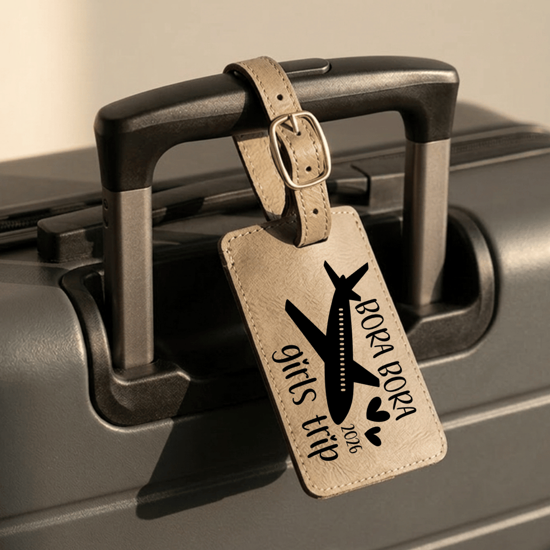 Luggage tag with 'Bora Bora girls trip 2026' text and airplane design on a suitcase.