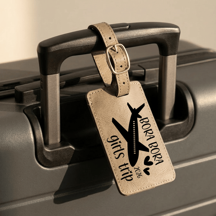 Luggage tag with 'Bora Bora girls trip 2026' text and airplane design on a suitcase.