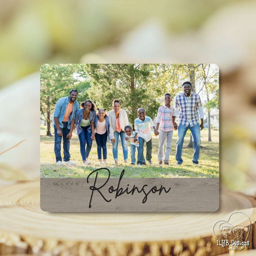 Family photo on a wooden plaque with 'Robinson' written on it, set against a blurred natural background.