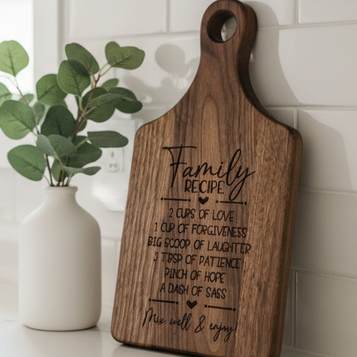 A wooden cutting board with a handle and engraved text reading &