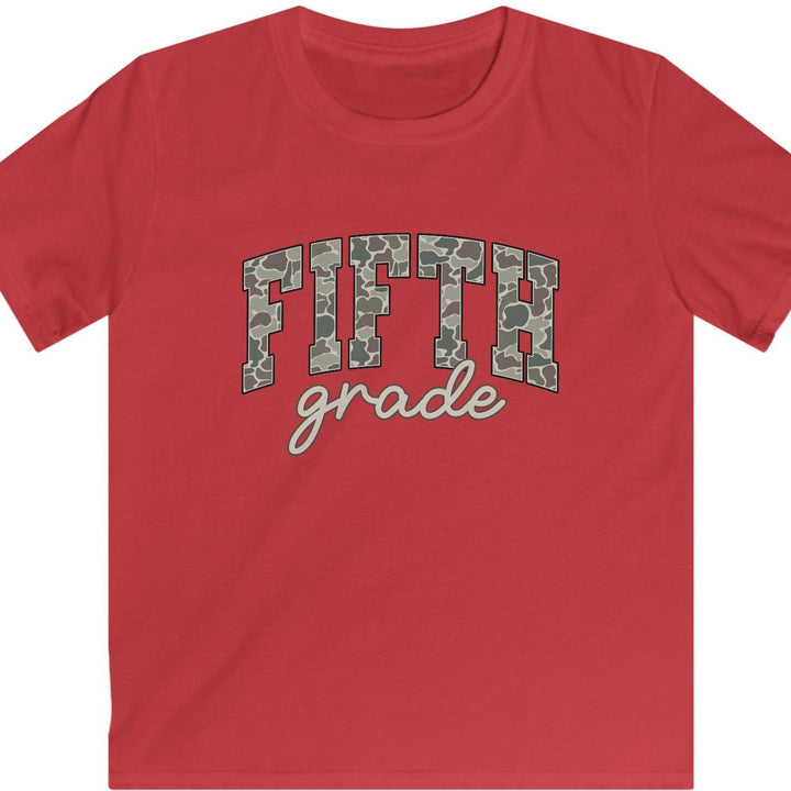 A red short-sleeve crewneck t-shirt featuring a graphic on the chest that reads 'FIFTH grade' in arched camouflage letters with tan cursive text underneath, displayed on a solid white background.