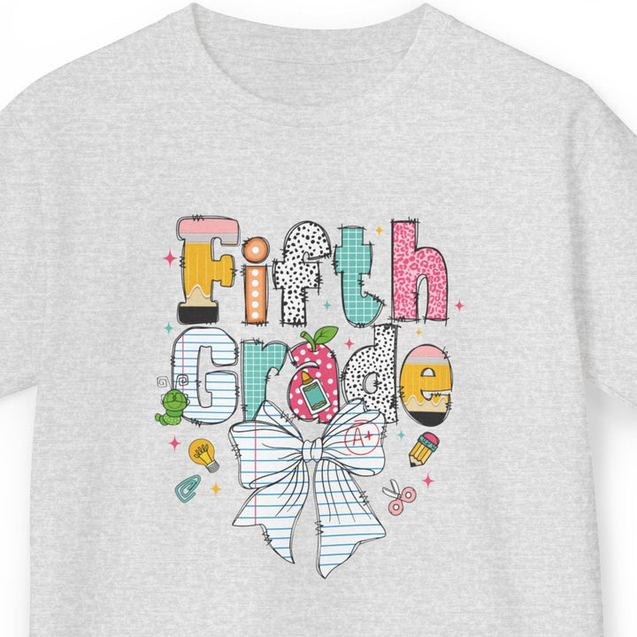 A light ash gray short-sleeve t-shirt with a colorful graphic on the front that reads 'Fifth Grade' in playful hand-drawn letters, featuring a striped bow, flowers, and small doodles, shown against a plain white background.
