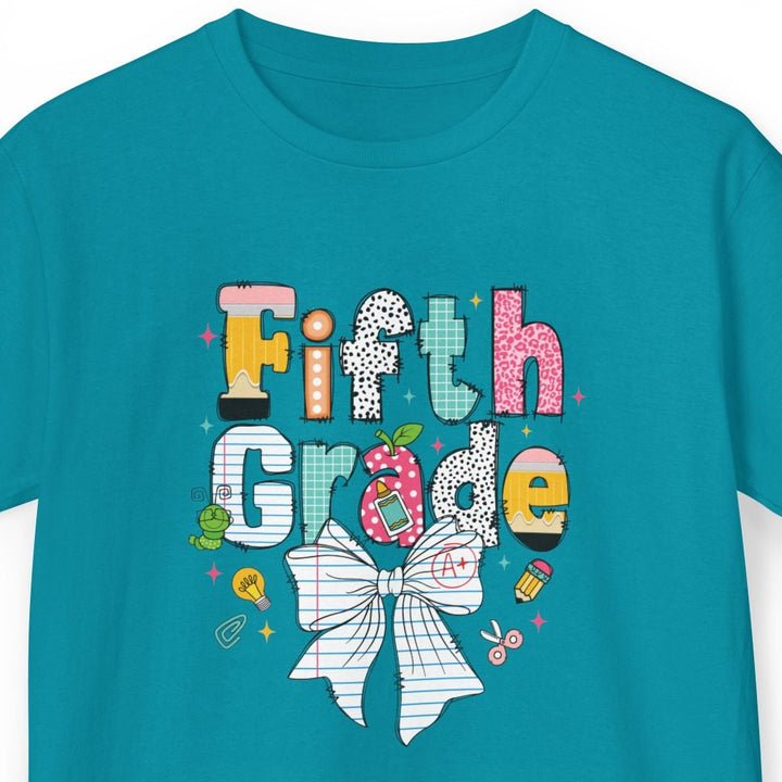 A teal short-sleeve t-shirt with a colorful 'Fifth Grade' graphic on the chest, featuring a white bow illustration and school-themed doodles, shown on a plain white background.