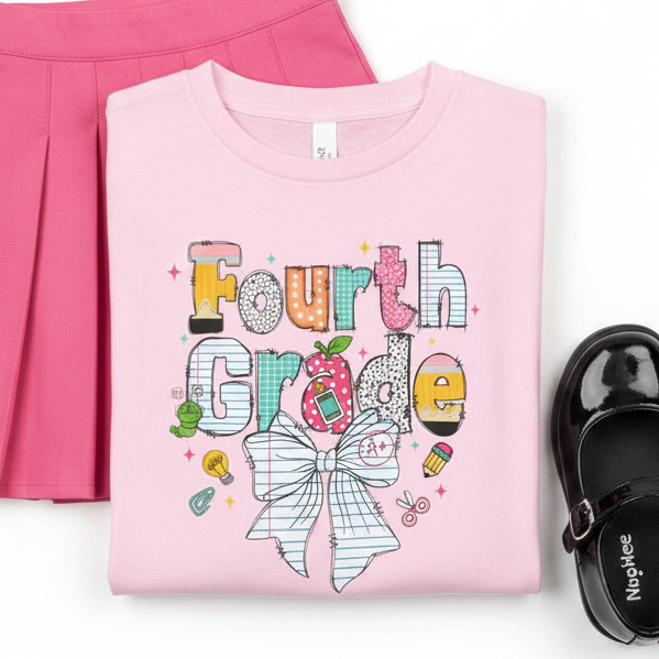 A light pink short-sleeve t-shirt with a colorful graphic on the front that reads 'Fourth Grade' in playful hand-drawn lettering, decorated with a white bow, and small school doodles, shown against a plain white background with pleated bright pink skirt and black shoes.
