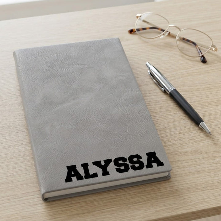 A gray faux-leather notebook with the name &