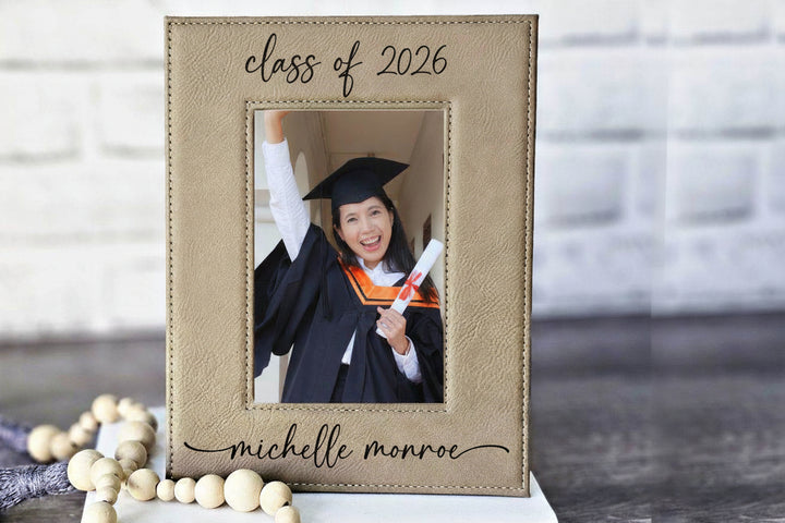 Graduation-themed photo frame with a picture of a graduate and 'class of 2026' text along with graduates name in a script font on the bottom