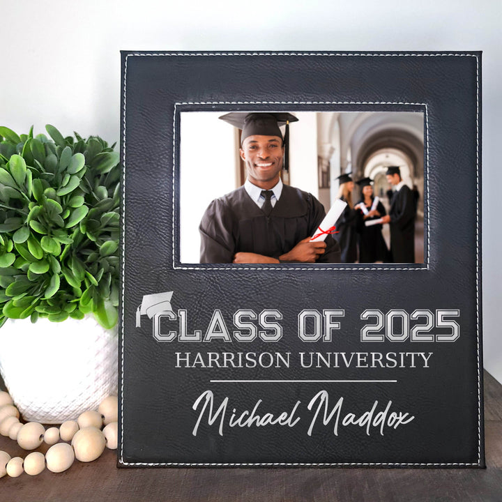 Graduation-themed black faux leather photo frame with a picture of a graduate, metallic silver engraved text 'Class of 2025 Harrison University', and name 'Michael Maddox'