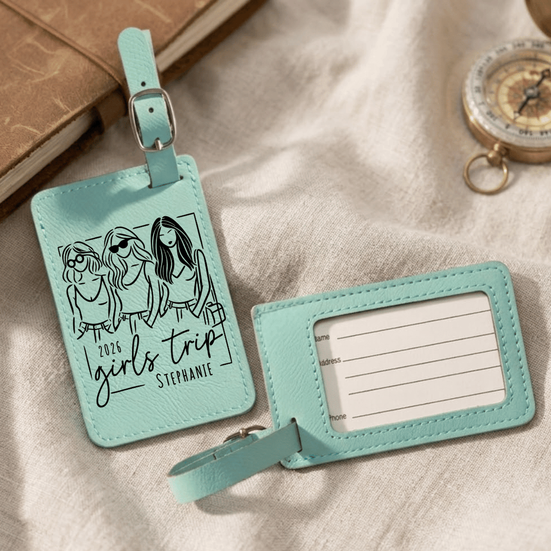 Two turquoise luggage tags with one featuring an illustration of three women and text, on a textured surface.