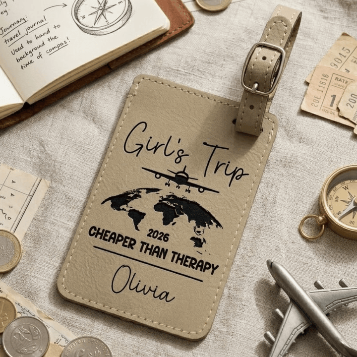 Beige luggage tag with travel-themed text and graphics on a surface with travel items.