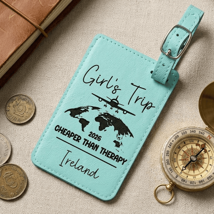 Turquoise luggage tag with travel-themed text and graphics on a textured surface with coins and a compass.
