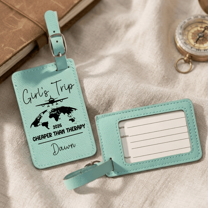 Two turquoise luggage tags with travel-themed text on a textured surface.