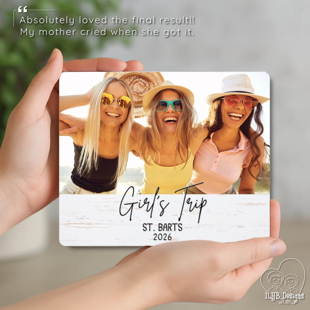 Three women on a 'Girl's Trip' to St. Barts 2026 photo board held by a hand.