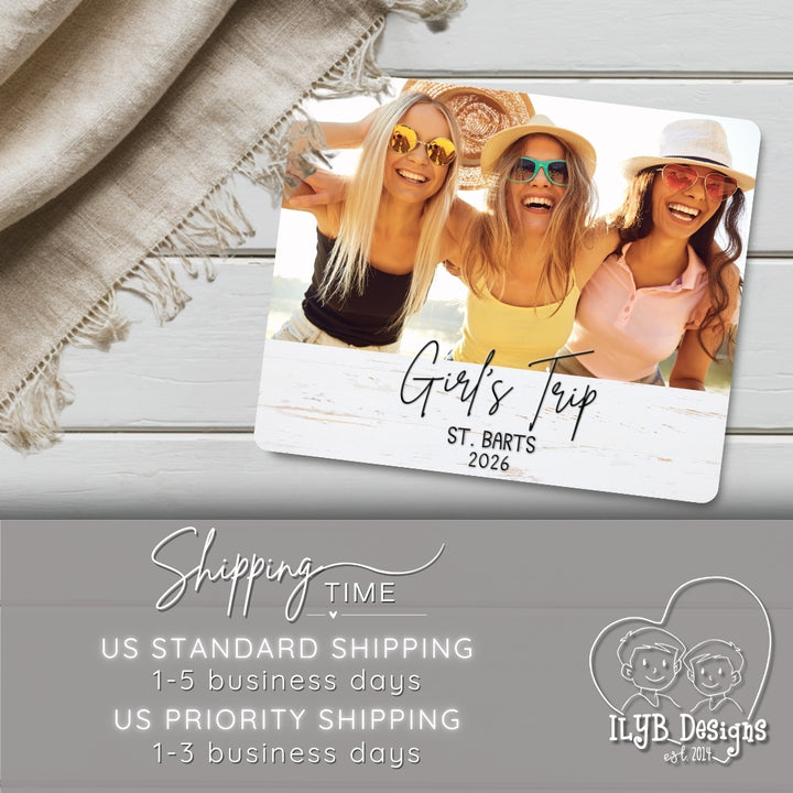 Photo plaque with three women on a beach, labeled 'Girls Trip St. Barts 2026', on a wooden surface with a blanket.