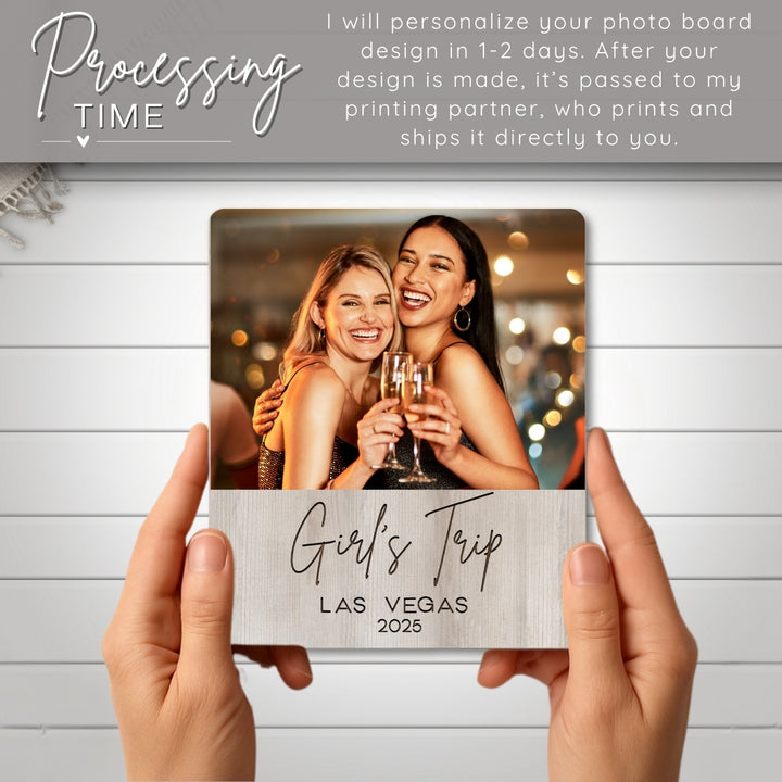 Personalized photo board with 'Girl's Trip Las Vegas 2025' text, held by hands against a light wooden background.