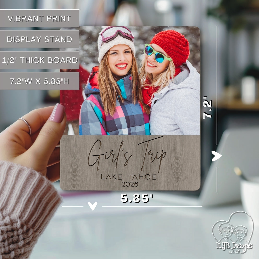 Wooden photo plaque with two people and 'Girl's Trip Lake Tahoe 2020' text, held by a hand.