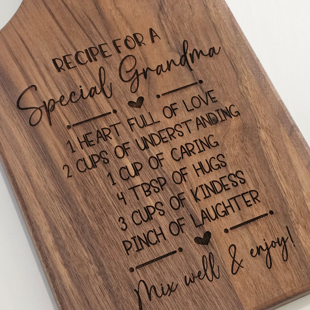 A rectangular wooden cutting board with engraved text that reads 'Recipe for a Special Grandma' followed by a recipe-style list of love, understanding, caring, hugs, kindness, and laughter, plus 'Mix well & enjoy!' on a white background.