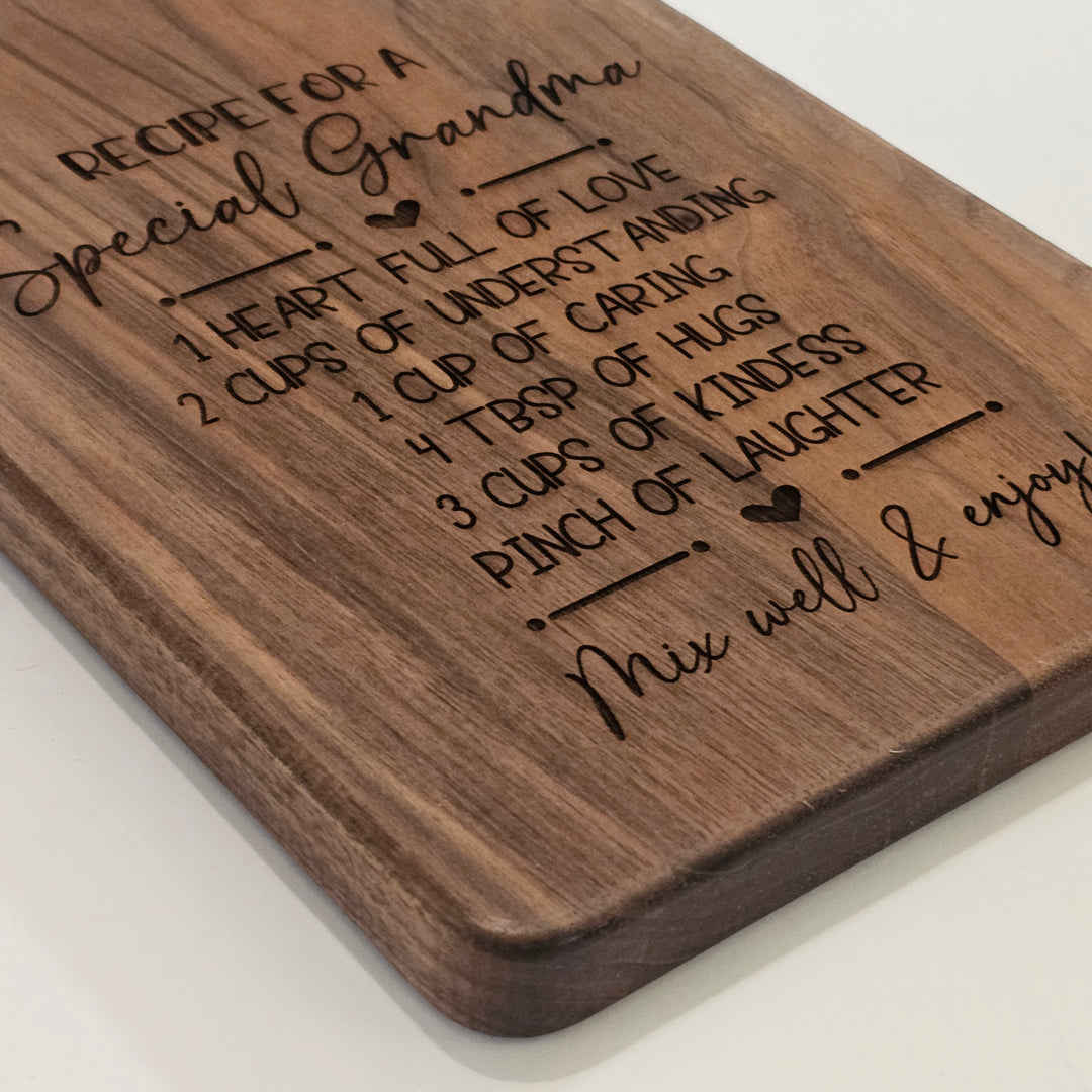 A rectangular wooden cutting board with rounded corners, featuring an engraved recipe for &