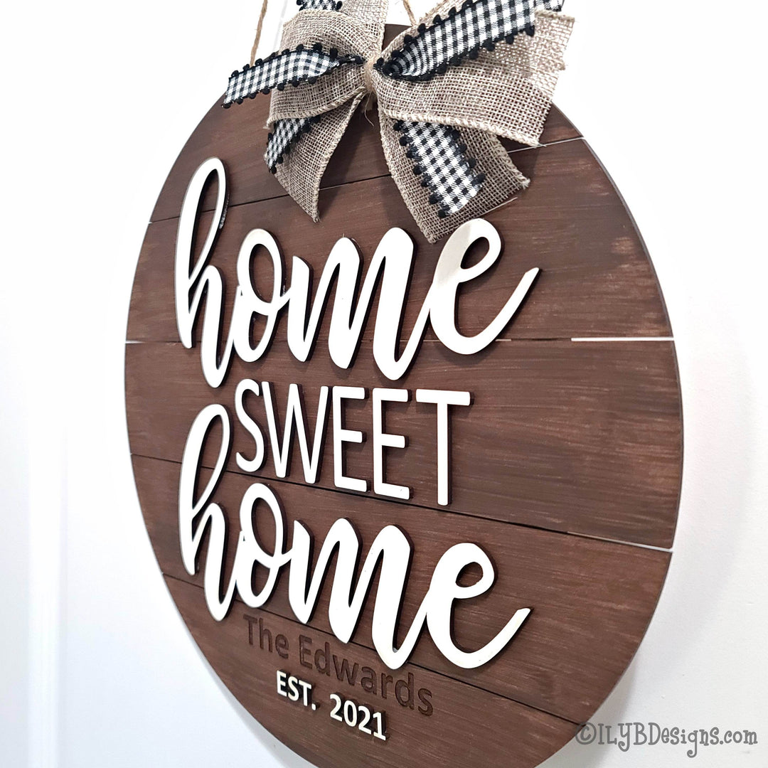 Wooden sign with 'home sweet home' text and a bow on a white background
