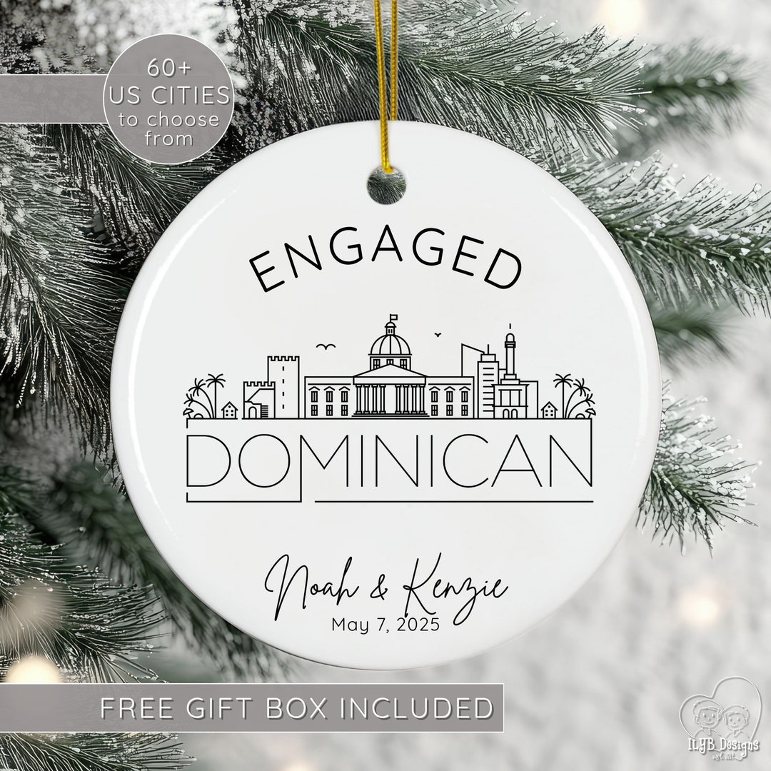 Engagement ornament with black and white line drawing of the Dominican international city skyline with name of city in a thin modern print font below skyline. Above city skyline is word "engaged" slightly curved to match the shape of the round ceramic ornament. Under the international city skyline drawing is the engaged couples names in a modern script font and underneath that is their personalized engagement date.