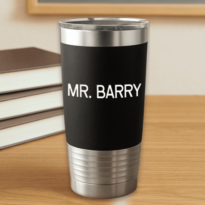 Black tumbler with 'MR. BARRY' text engraved in white sitting on a wooden surface