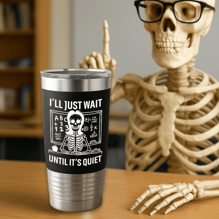 Tumbler with a skeleton design and text next to a skeleton figure on a table.
