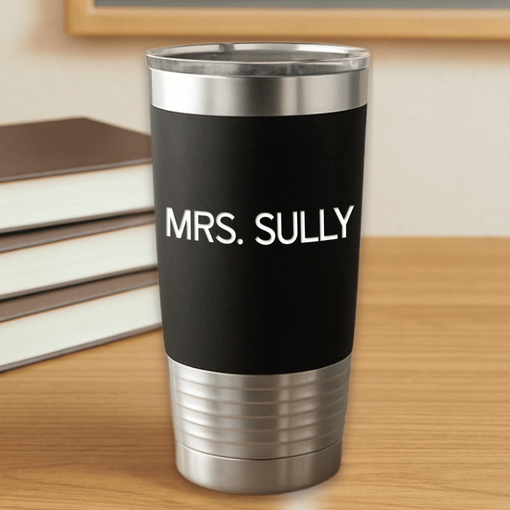 Black tumbler with 'MRS. SULLY' text engraved in white sitting on a wooden surface