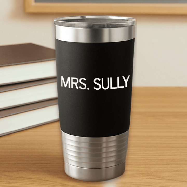 Black tumbler with 'MRS. SULLY' text engraved in white sitting on a wooden surface