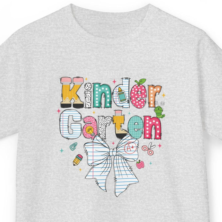 A light heather gray short-sleeve t-shirt with a colorful graphic on the front that reads 'Kinder Garten' in playful multicolored letters above a white bow illustration, shown on a plain white background.