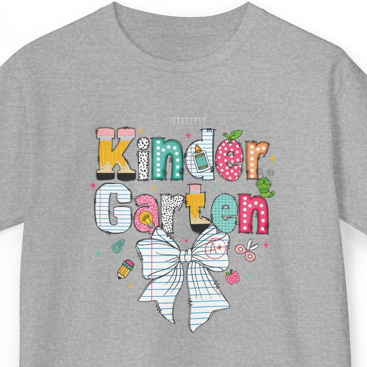A heather gray short-sleeve t-shirt with a colorful graphic on the front that reads 'Kinder Garten' in playful multicolored letters, decorated with a white bow and small garden-themed doodles, shown on a plain white background.