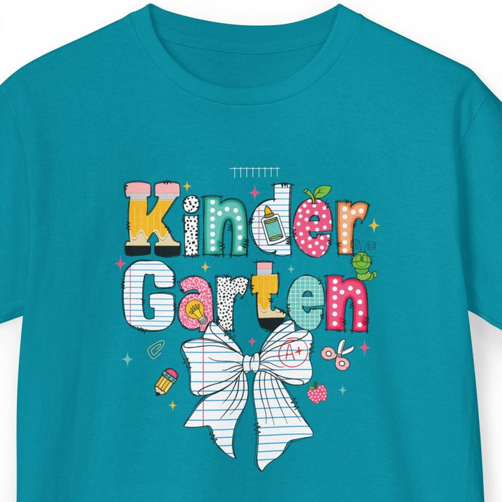 A teal short-sleeve t-shirt with a colorful graphic on the chest that reads 'Kinder Garten' in playful multicolored letters, decorated with a white bow and small flowers, shown on a plain white background.
