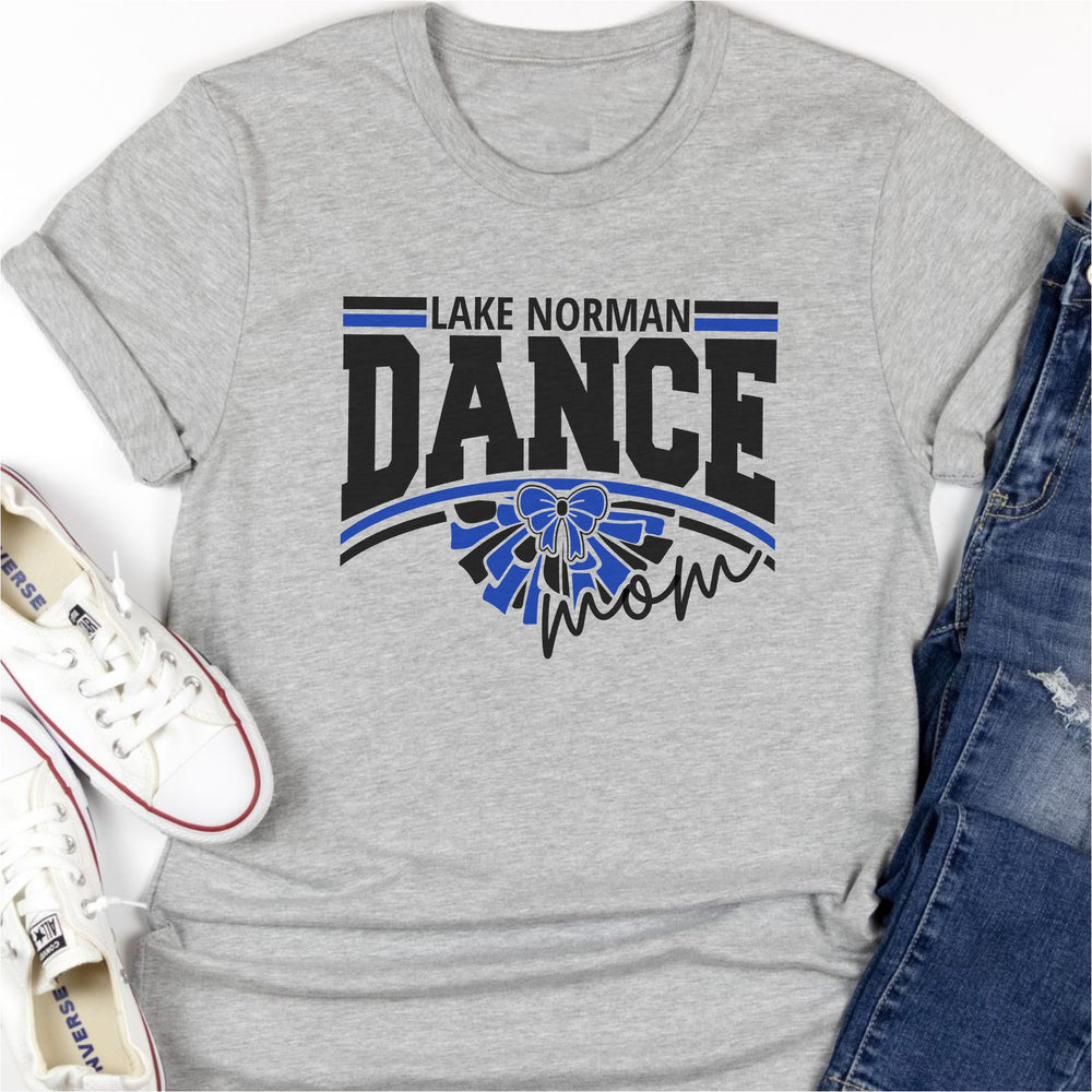 Gray t-shirt with 'Lake Norman Dance Mom' text and blue bow graphic, paired with white sneakers and blue jeans.
