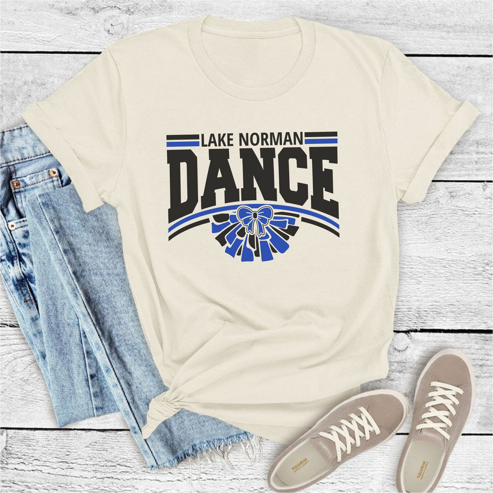 Beige t-shirt with 'Lake Norman Dance' design, paired with jeans and shoes on a wooden surface.