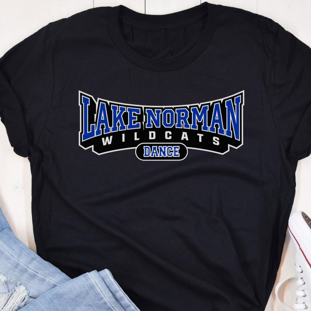 Black t-shirt with 'Lake Norman Wildcats Dance' text on a wooden surface with jeans and sneakers.
