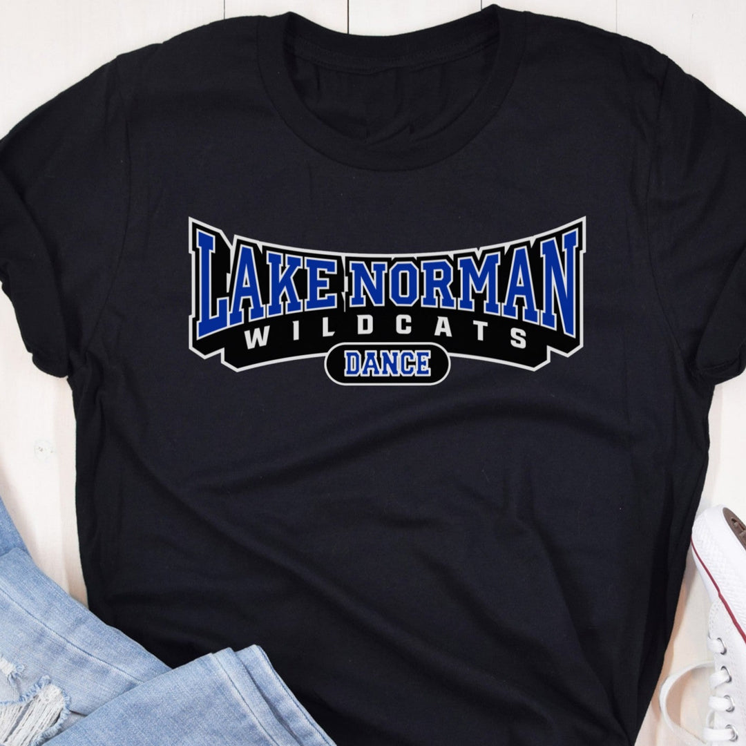 Black t-shirt with 'Lake Norman Wildcats Dance' text on a wooden surface with jeans and sneakers.