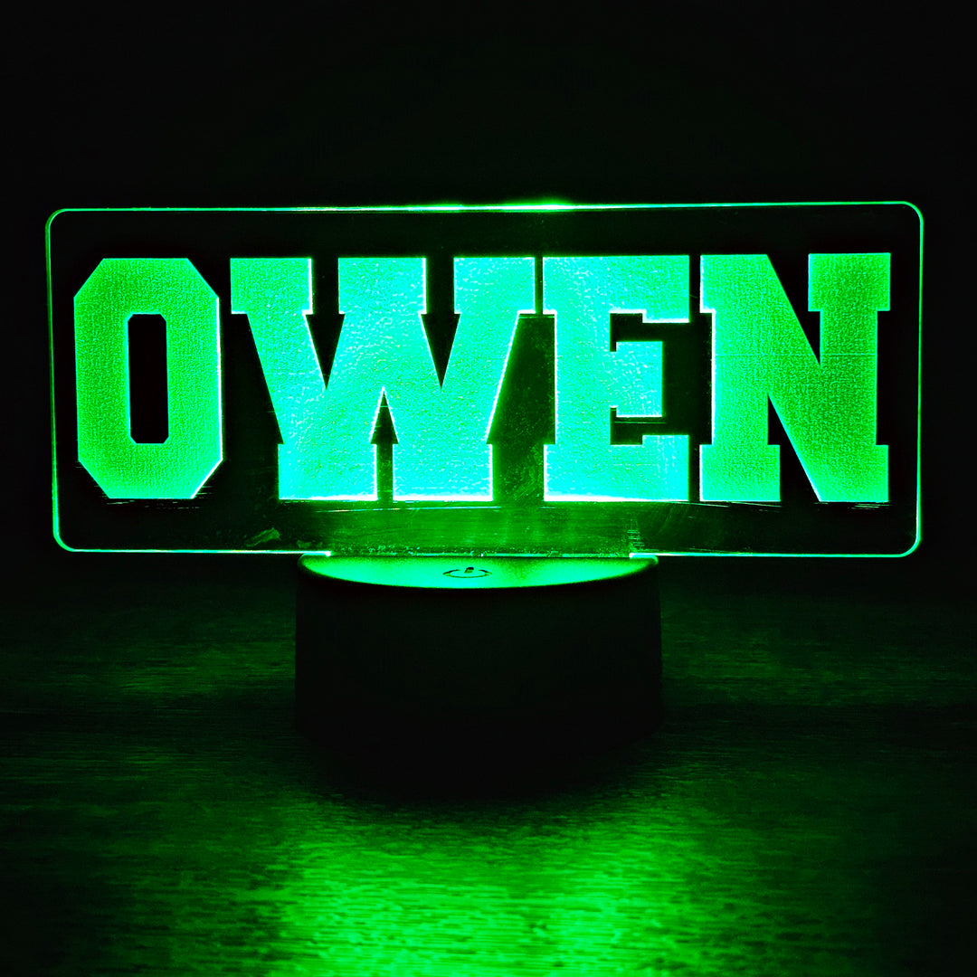 Green LED night light with 'OWEN' engraved on acrylic on a dark background