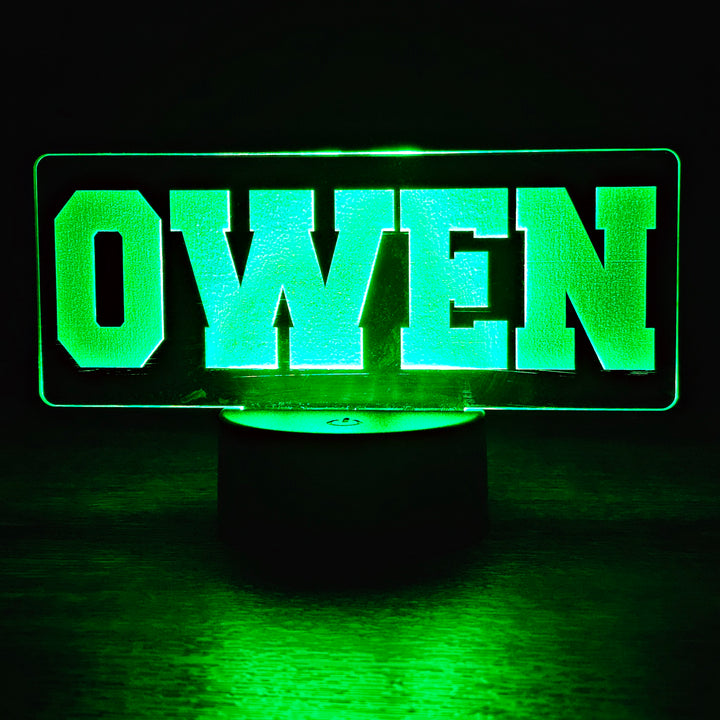 Green LED night light with 'OWEN' engraved on acrylic on a dark background