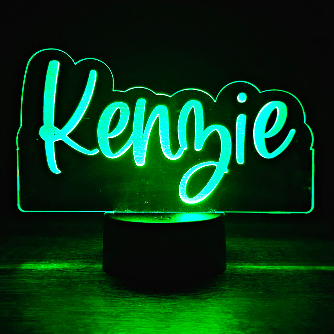 LED night light with the name 'Kenzie' engraved in a script font on acrylic lit in green in a black background