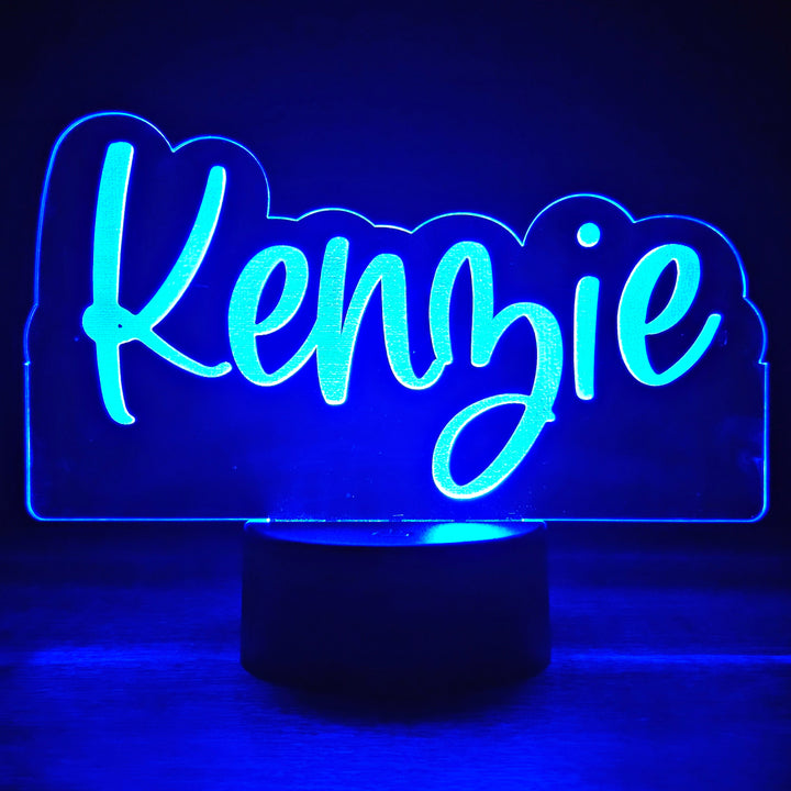 LED night light with the name 'Kenzie' engraved in a script font on acrylic lit in blue in a black background
