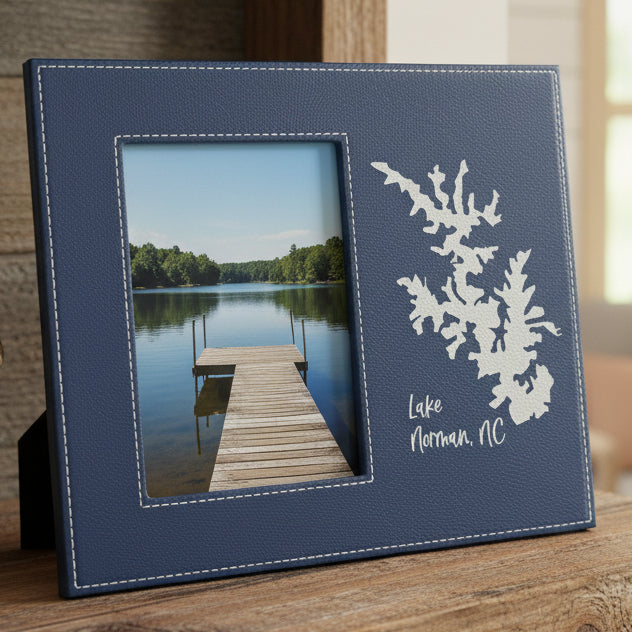 A navy blue faux-leather picture frame with white stitching, featuring a metallic silver engraving of the silhouette of Lake Norman  with text &