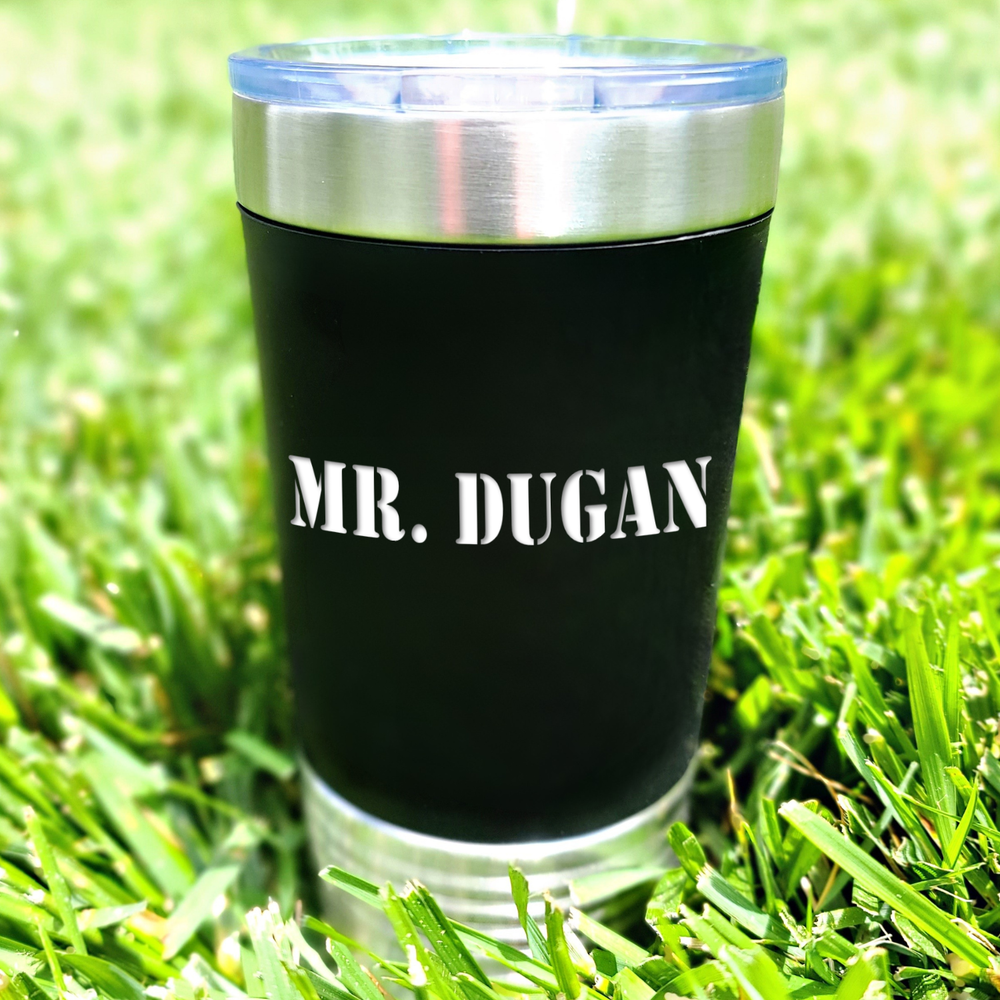 black Polar Camel 20oz stainless steel tumbler sitting in grass with the name 'Mr. Dugan' engraved in white