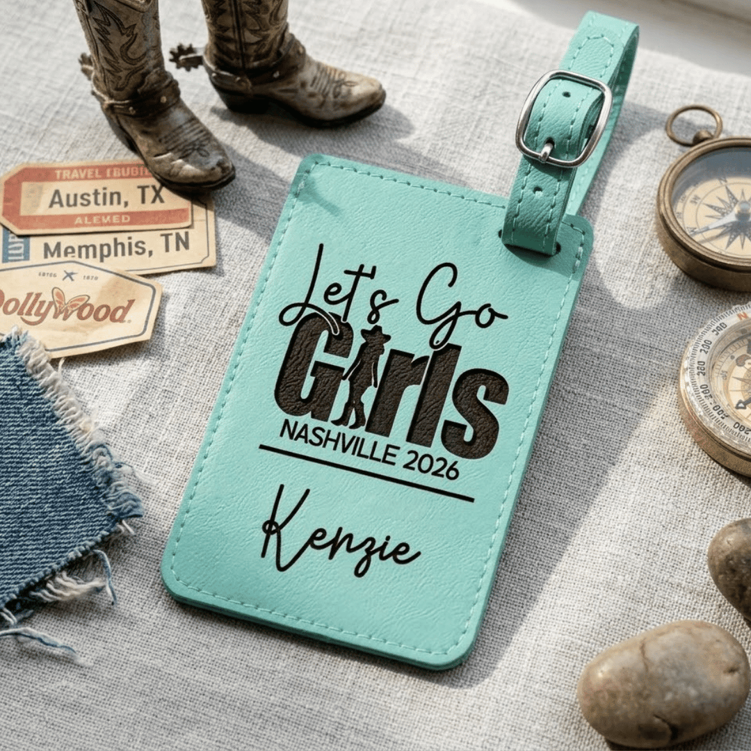 Turquoise luggage tag with 'Let's Go Girls Nashville 2026 Kenzie' text on a textured surface with travel-themed items.